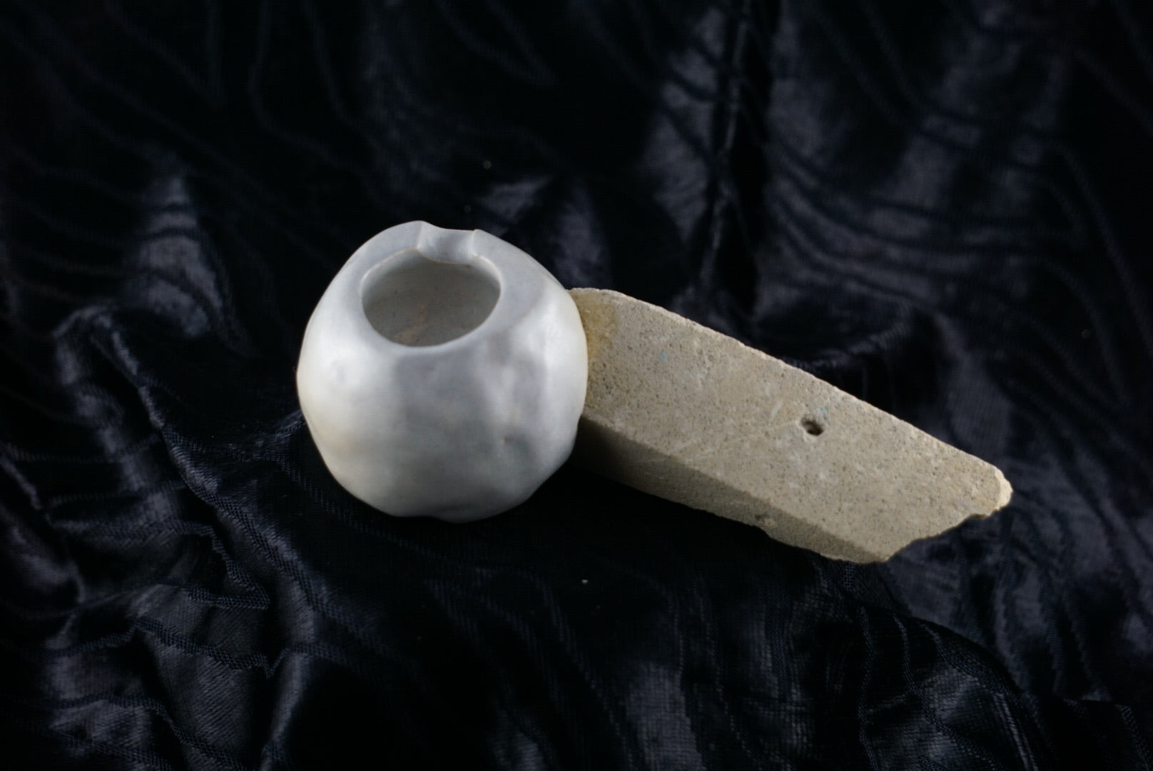 Small, handmade, grey ceramic ashtray molded around a piece of yellow brick