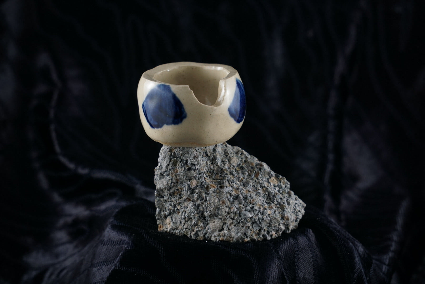 Small, handmade, white and blue ceramic ashtray molded around a piece of black rock