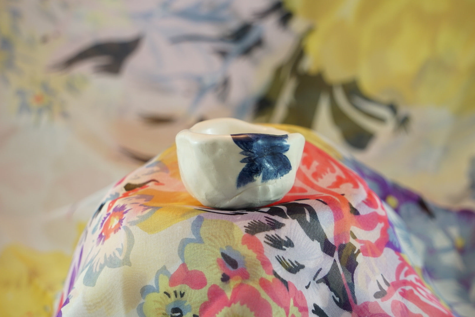 Small, handmade white ceramic pinch pot with loosely drawn blue insects. 